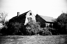 Ulica Dąbrowskiego : stare zabudowania mieszkalno-gospodarcze z nowym, piętrowym budynkiem mieszkalnym w tle